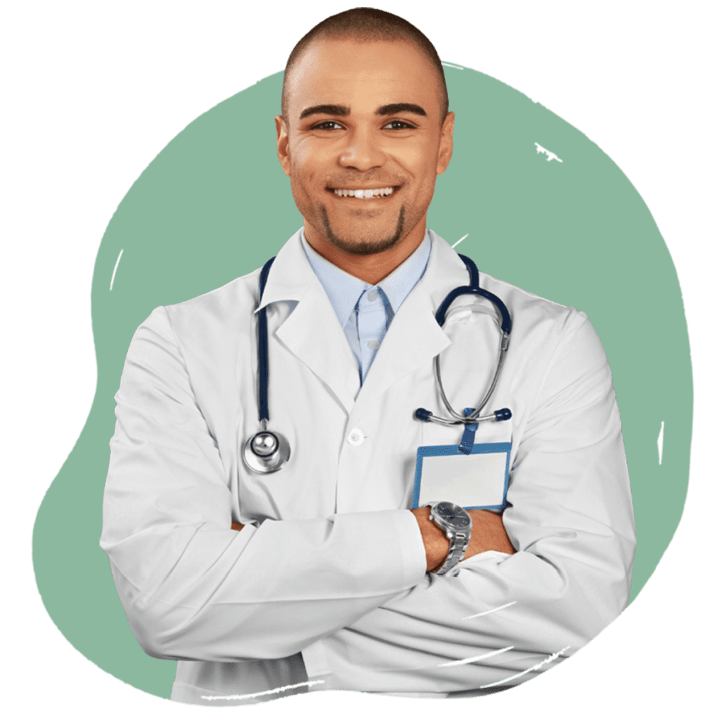 A young male doctor smiling while wearing a white coat, stethoscope, and a name badge. He is standing with his arms crossed and a green background.