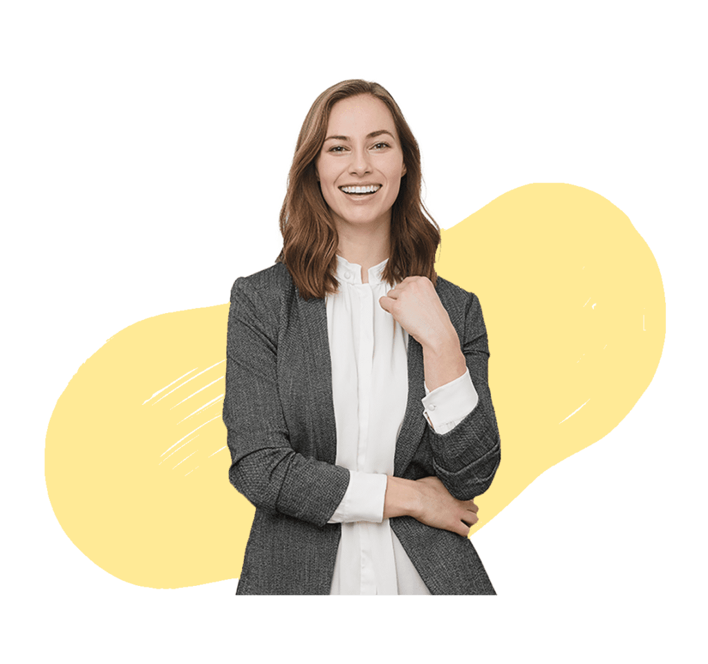 A professional woman wearing a suit, standing with one fist raised, and smiling with an yellow background.