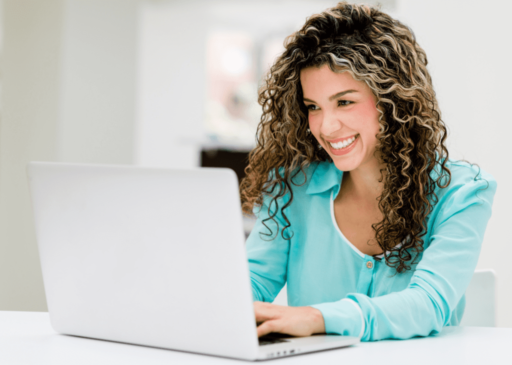 A woman smiling while working on her laptop, symbolizing the efficiency and ease of using Checksome for primary source verification and credentialing tasks.