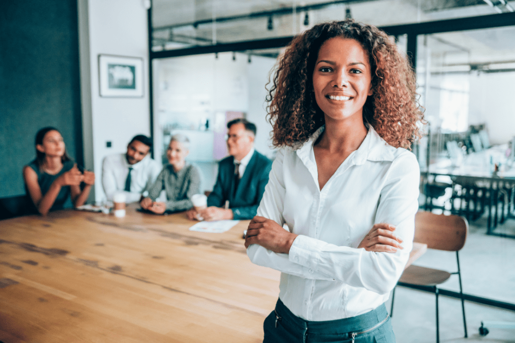 A women smiling in a board room dislaying women leaders.