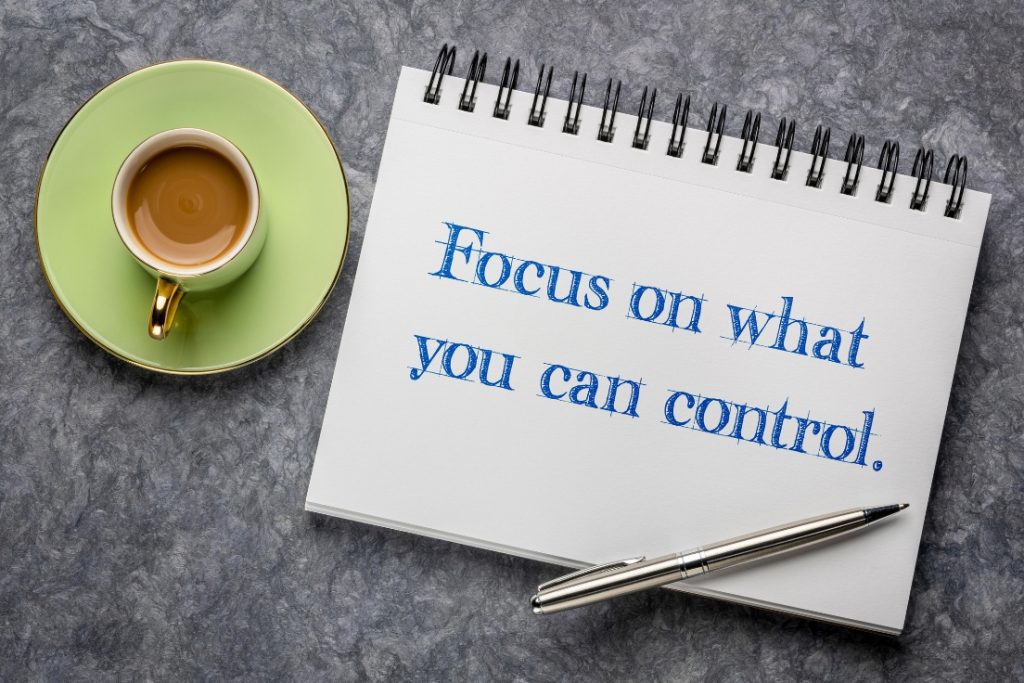 Notepad that says focus on what you can control next to a cup of coffee on a saucer