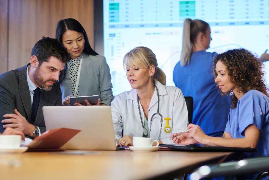 Picture of people gathered around a laptop discussing something.