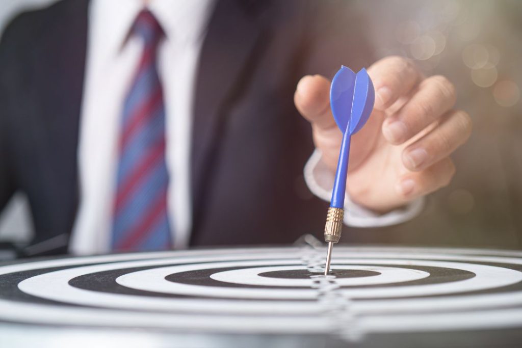 Photo of a man in a suit throwing a dart on a bullseye